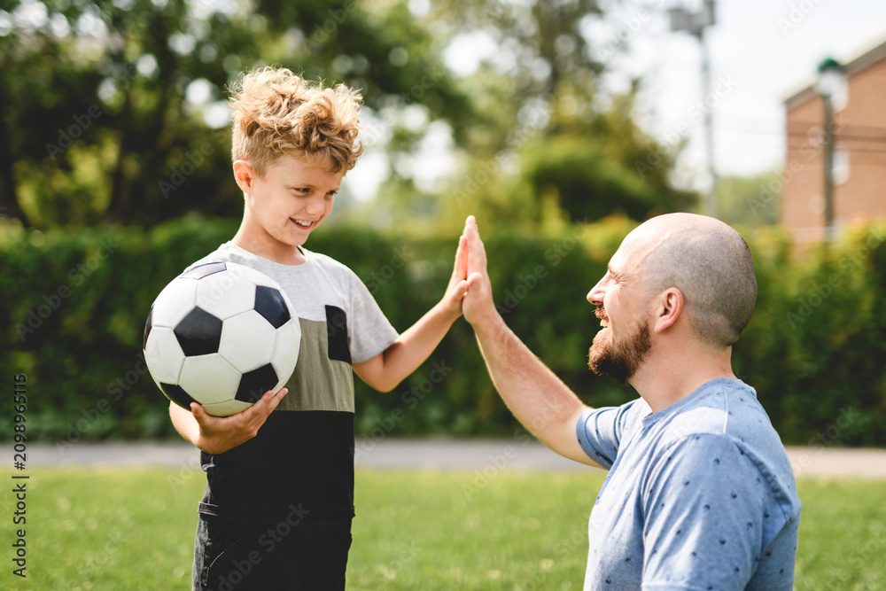 Obraz premium man with child playing football outside on field