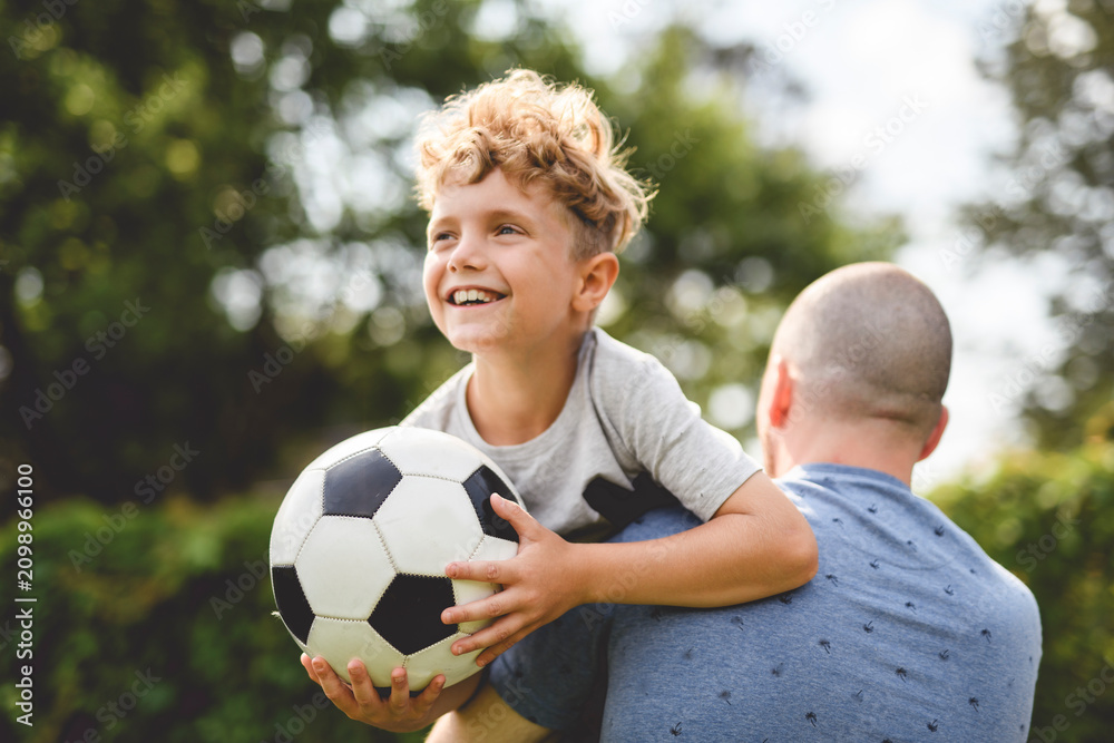 Obraz premium man with child playing football outside on field