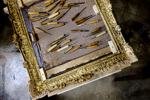 Obraz na plátně Traditional wood carving chisels on ornate antique frame in artisan workshop