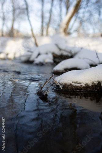 Obraz na plátne Snow-Covered Rocks Along Winter Stream, Low Angle Water View
