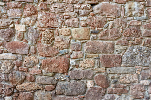 Rustic red and brown stone wall texture of an old medieval house in Mura, Catalonia, Spain