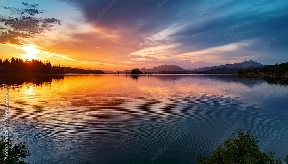 Obraz premium Sunset Over A Lake With Calm Waters