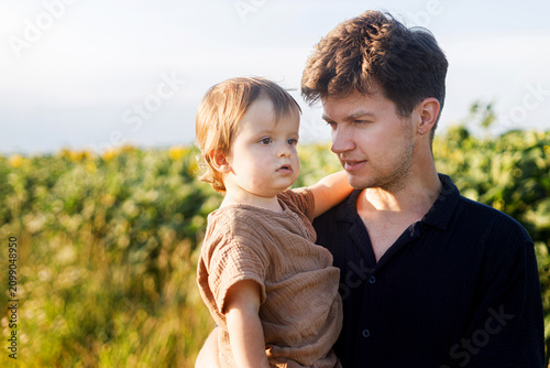 Bild auf Leinwand Happy father walking with son in sunny summer field