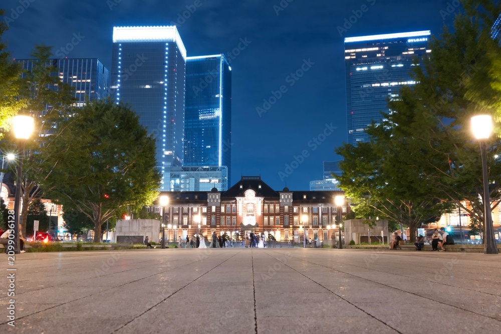 Fototapeta premium ライトアップされた東京駅丸の内駅舎と高層ビルが輝く夜景 Illuminated Tokyo Station Marunouchi Building with glowing modern skyscrapers at night 