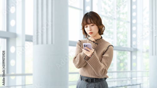 スマートフォンを使って考える女性・ビジネスウーマン, Businesswoman Thinking While Using a Smartphone