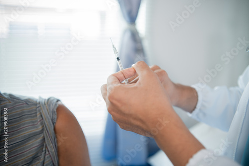 Foto A male healthcare worker wearing gloves safely administers a vaccine to promote disease prevention, well-being, research, and attentive patient care in a clinical setting