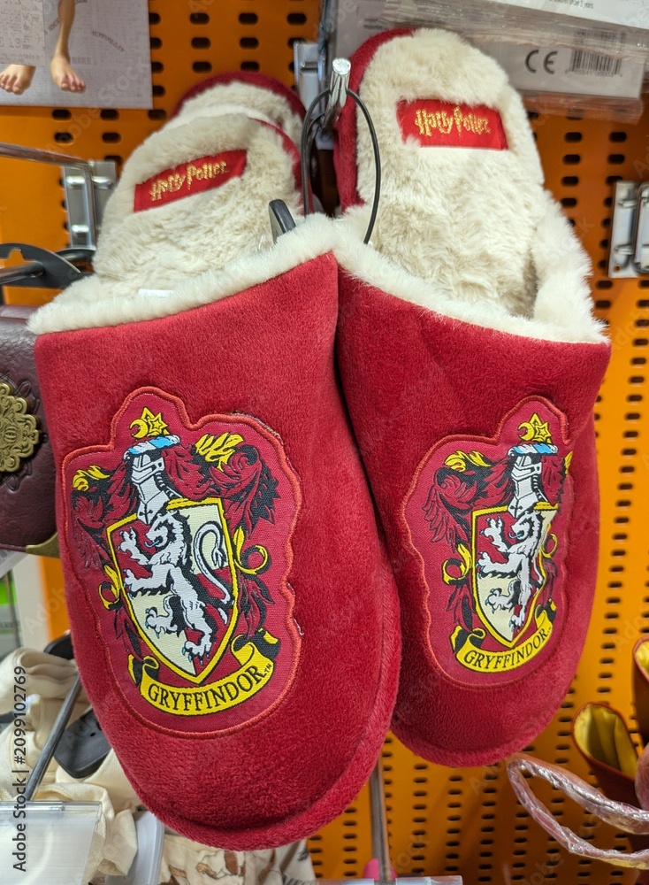 Fototapeta premium Par de pantuflas de color rojo con el logo de Harry Potter y el escudo de la Casa de Gryffindor del Colegio Hogwarts de Magia y Hechiceria, tienda Toy Planet de Madrid, España, 15 de mayo de 2026