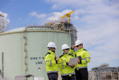 Engineers collaborating at a construction site lng facility team discussing project plans under clear blue sky
