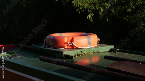 Fotografía Lifebuoy on canal boat roof, orange life ring with reflective tape, safety equip