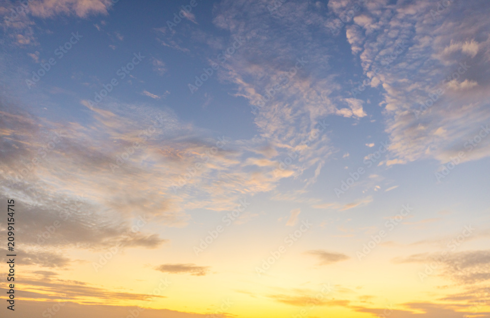 Obraz premium Dramatic golden hour sky with soft clouds at sunset,A beautiful and serene view of a golden hour sky, featuring soft, wispy clouds illuminated by the warm, gentle light of the setting sun, creating.