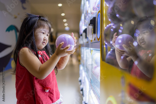 Konstfotografi Little Girl Excitedly Holding a Toy Capsule from a Gashapon Machine,A young Asia
