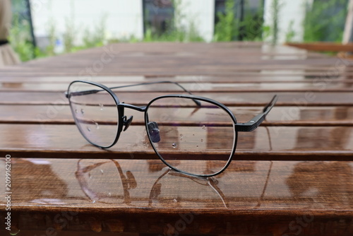 Foto Glasses lying on a garden table after rain, wet surface, weather outside, autumn