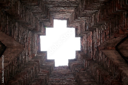 Abstract Brickwork Sky View: An abstract perspective looking directly up into a geometric ceiling made of brick, with a bright square of sky visible through the opening.
