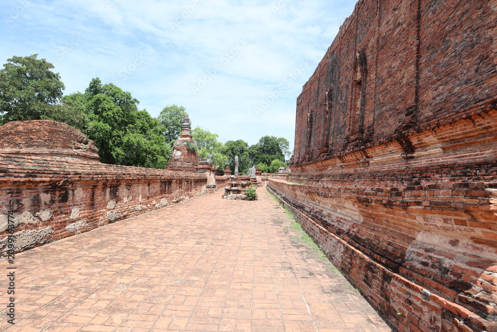 Fototapeta premium Ancient Temple Ruins in Asia: An atmospheric perspective of weathered brick walls and ancient stupas, with lush greenery in the background.