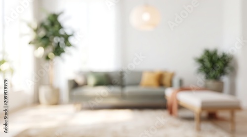 Bright modern living room with blurred focus on comfortable grey sofa and green indoor plants creating serene atmosphere for interior design concept with soft natural daylight streaming in
