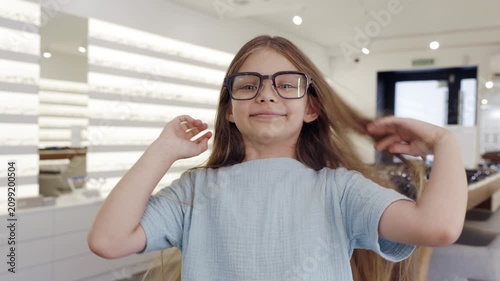Cheerful girl experiments with glasses in bright optical shop environment