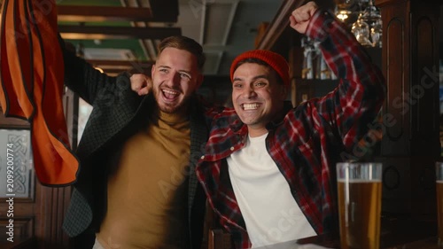 Joyful group of friends celebrating goal while watching football game in cozy pub environment