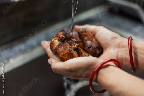 Indian female hands washing boiled taro roots in kitchen sink