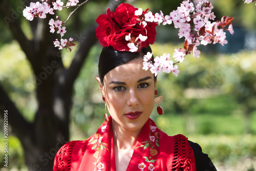 Portrait of a beautiful woman dancing flamenco in Seville, Spain. She is wearing a black gypsy dress with ruffles and a flower in her hair. Flamenco, a UNESCO Intangible Cultural Heritage.