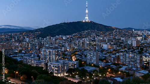 Night skyline view of Tbilisi with illuminated TV tower atop Mtatsminda Mountain during twilight hours