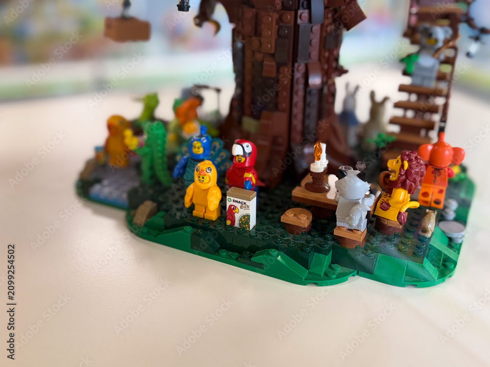 Obraz premium Lego minifigures gathered around a tree in a forest scene with small props and colorful characters on a tabletop display.