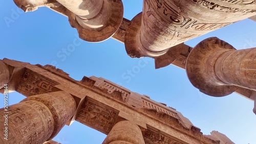 rolling shot of Impressive low angle perspective moving through the monumental papyrus columns of the great hypostyle hall at karnak temple complex in luxor