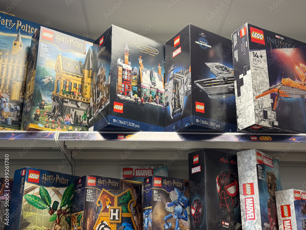 Fototapeta premium Assorted lego toy boxes on store shelves in a retail shop, featuring harry potter, marvel and fantasy themed building sets.