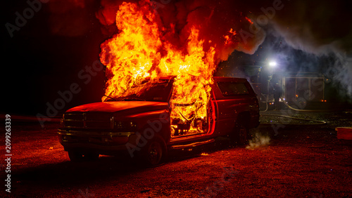 Принти на полотні Firefighters work to control a large fire coming from a vehicle