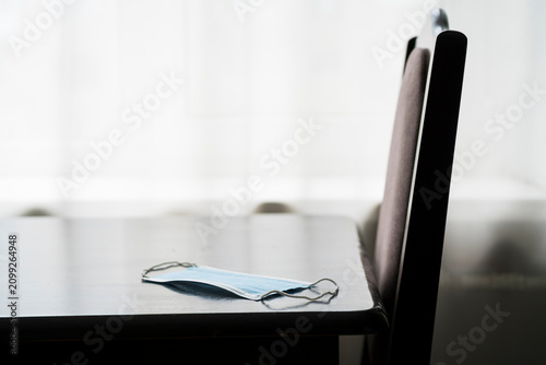 Blue medical protective face mask lying on a wooden table in a room
