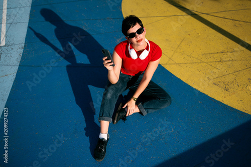 Woman using smartphone and headphones on colorful urban ground