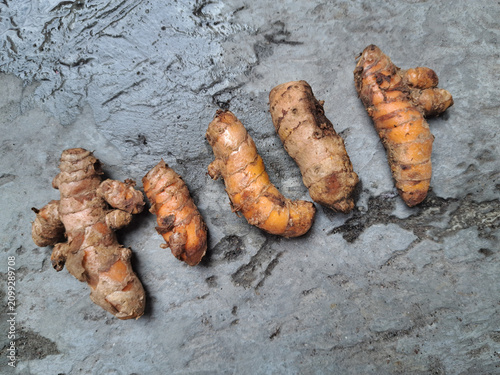 Bild auf Leinwand Fresh turmeric rhizomes arranged on a rustic concrete surface, showcasing natural spice roots with organic texture, ideal for culinary, herbal, and healthy lifestyle concepts
