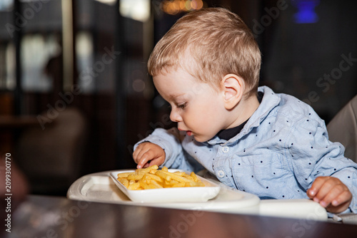 little toddler having french fries meal in cafe