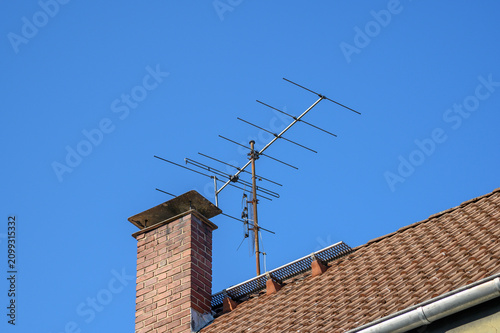 Residential roof with a brick chimney, television antenna, and snow guard