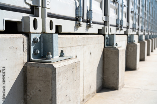 Shipping containers secured on concrete foundations with metal brackets and bolts