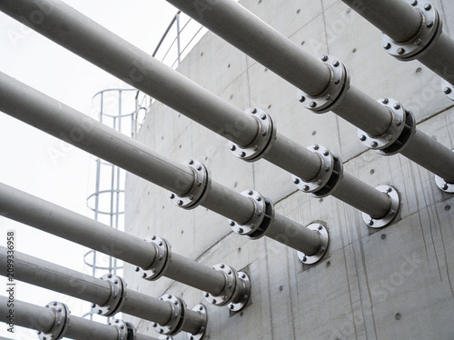 Foto Industrial pipes attached to a concrete wall with visible flanges and bolts