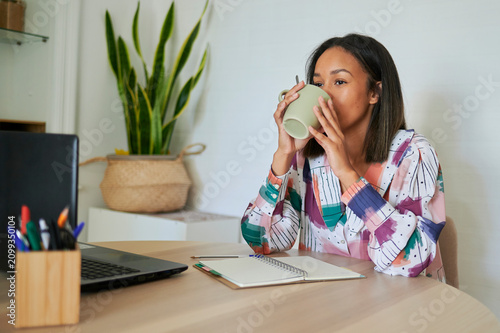 Fényképezés Woman drinking coffee while working from home office