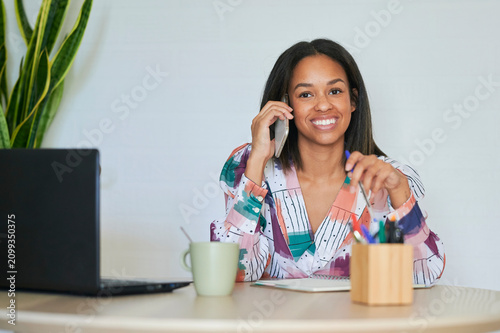 Foto Manager talking on phone and smiling during remote work at home office