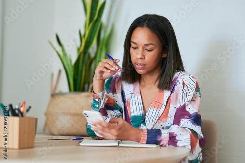 Cuadro en lienzo Focused businesswoman using smartphone and thinking in home office