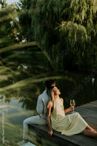 Obraz na płótnie Couple enjoying a tranquil evening by the water under soft sunlight