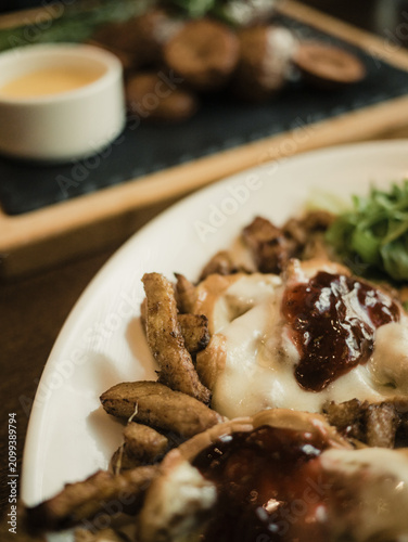Close-up of appetizing hot dish with roasted potatoes, melted cheese and cranberry sauce served in a restaurant