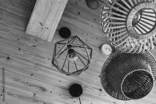 Black and white low angle shot of modern and rustic hanging lamps made of rope, bamboo and metal on a wooden ceiling