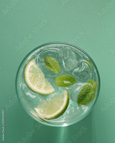 Minimal mojito cocktail with glowing sunlight reflections and fresh lime top view