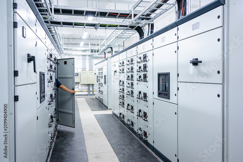 Canvas Print Industrial electrical control panel room with a technician checking equipment