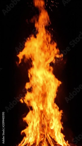 Intense orange fire flames rising vertically with sparks isolated on a black background