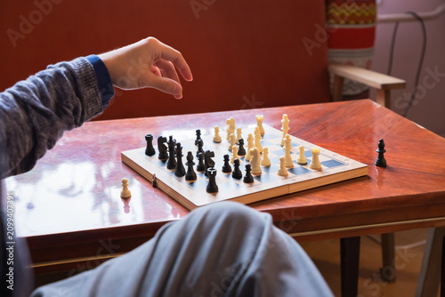 Fotografie Man playing chess on wooden table