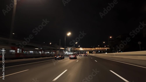 Nighttime urban highway drive with converging lanes under twilight sky