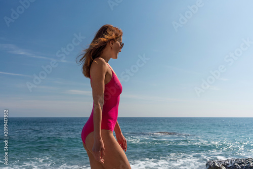 Photography Woman swimsuit ocean, adult standing on rocky shoreline looking at blue tranquil