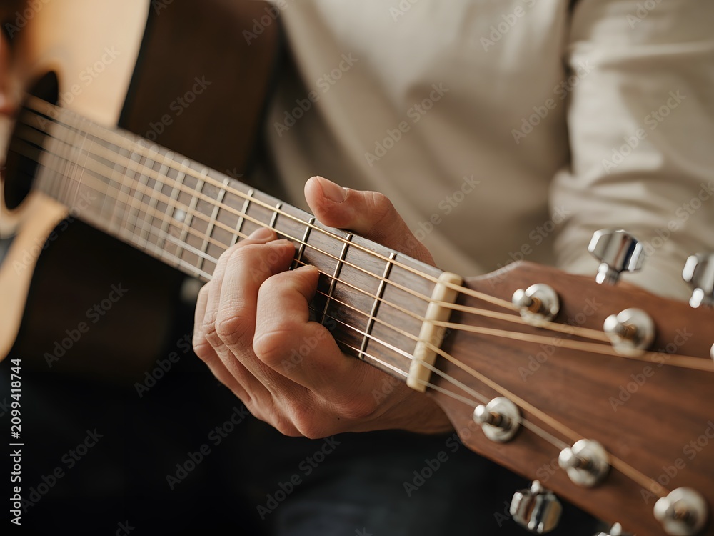 Fototapeta premium Close up of a musician playing acoustic guitar, hands on fretboard, music practice session.