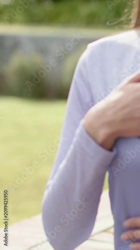 Vertical video: Camera panning, woman placing hand on chest on bench, lilac top, copy space
