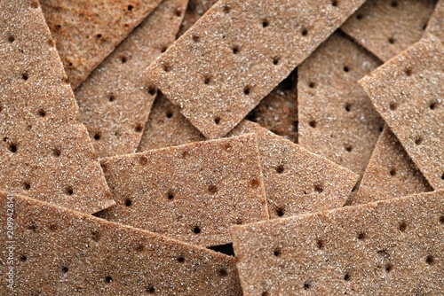 Dark brown crispbreads in big pile close up. Background of crispy bread squares
